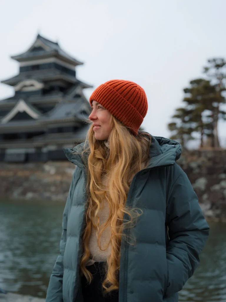Portrait of Brittany Sneller, author of Nomad in Japan travel blog, standing in front of Matsumoto Castle, Nagano, Japan.