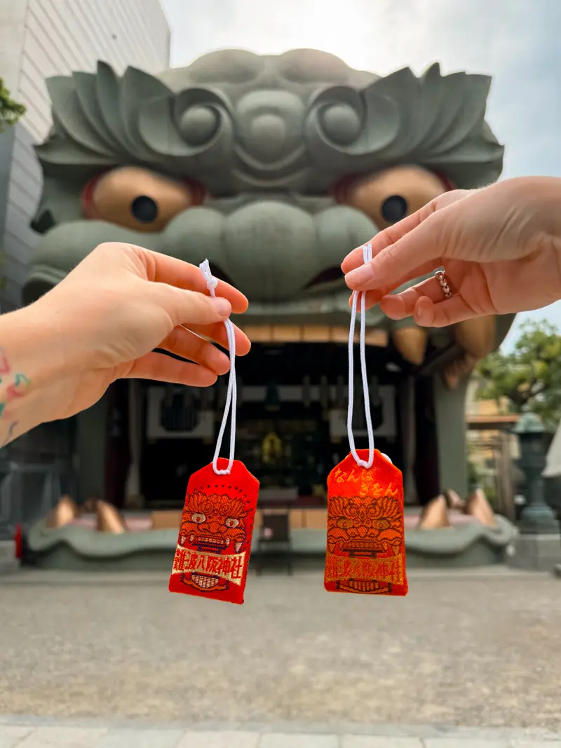 Sisters holding red and orange omamori (Japanese amulets) at the lion head shrine, Namba Yasaka Jinja, in Osaka, Japan.