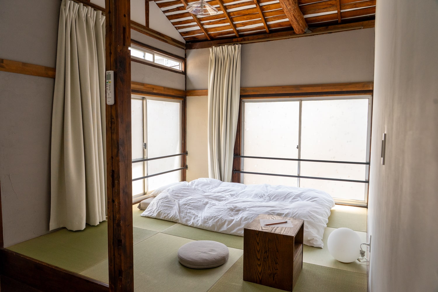 A minimalist traditional Japanese room with a futon bed on tatami flooring and soft natural light.